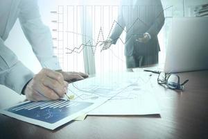 business documents on office table with smart phone and laptop and two colleagues discussing data in the background photo