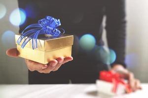 gift giving,man hand holding a gift box in a gesture of giving.blurred background photo