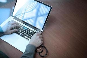 top view of Medicine doctor hand working with modern computer and smart phone on wooden desk as medical concept photo