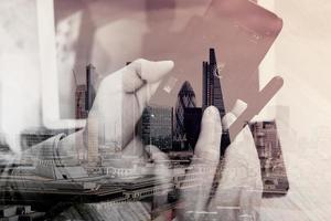 Double exposure of Hand using mobile payments online shopping,omni channel,icon customer network,in modern office wooden desk,London city buildings,eyeglass photo