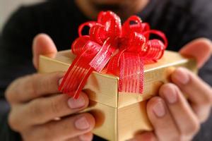 gift giving,man hand holding a gift box in a gesture of giving.blurred background,vintage effect photo