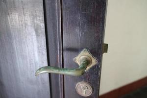 mango de hierro en la puerta de madera antigua foto