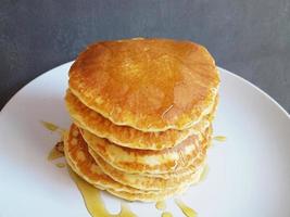 arrangement of pancakes on a white plate with melted honey