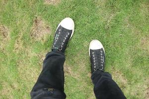 man wearing black pants and black shoes standing on the grass photo