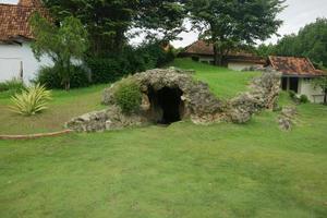 artificial cave in the middle of the park with green grass photo