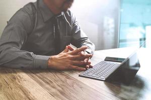 businessman working with new start up project.using smart phone digital tablet docking smart keyboard and laptop computer on wooden desk,sun effect photo