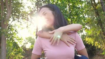 söt ung dotter på en piggy back ride med sin mamma utomhus park. asiatisk mamma piggybacks hennes lilla söta dotter njuter av roliga aktiva lektider tillsammans. video