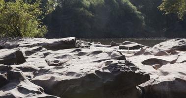 Natural waterfall full of rocks in hot sunny day. Surrounded with lush green forests. video