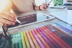 Website designer working digital tablet and computer laptop with smart phone and digital design diagram on wooden desk as concept photo