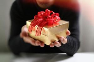 entrega de regalos, mano de hombre sosteniendo una caja de regalo en un gesto de dar. fondo borroso, efecto vintage foto