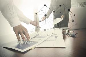 business documents on office table with smart phone and digital tablet and stylus and two colleagues discussing data in the background photo