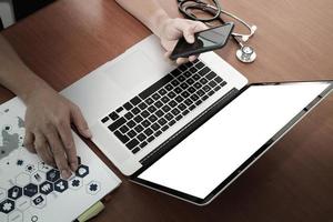 top view of Medicine doctor hand working with modern computer and smart phone on wooden desk as medical concept photo