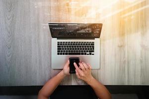 top view of Designer hand working with laptop computer and smarth phone and digital tablet on wooden desk as responsive web design concept photo