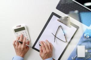 vista superior del concepto de costos y tarifas de atención médica. La mano de un médico inteligente usó una calculadora para costos médicos en un hospital moderno foto