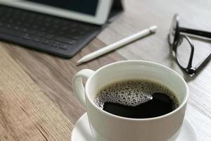 Coffee cup and Digital table dock smart keyboard,eyeglasses,stylus pen on wooden table,filter effect photo