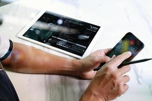 mano de hombre de negocios trabajando en computadora portátil y tableta digital y teléfono inteligente en escritorio de mármol como concepto