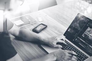 designer hand attending video conference with laptop computer and smart phone at desk in office photo