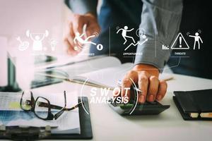 businessman hand working with finances about cost and calculator and latop with mobile phone on withe desk in modern office photo