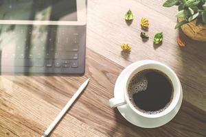 Coffee cup and Digital table dock smart keyboard,vase flower herbs,stylus pen on wooden table,filter effect photo