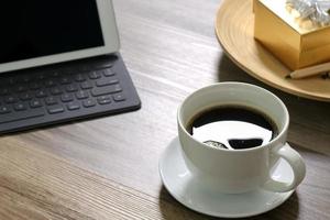 taza de café y teclado inteligente para base de tableta digital, caja de regalo dorada y bandeja de madera redonda, lápiz de color sobre mesa de madera foto