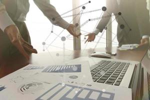 business documents on office table with smart phone and digital tablet and stylus and two colleagues discussing data in the background photo