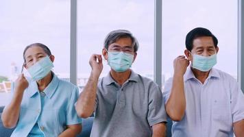 Group of senior people taking off protective face masks in a retirement home video