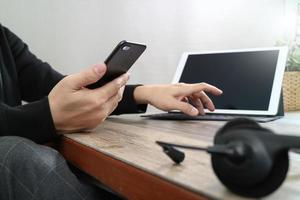 mano de hombre usando auriculares voip con teclado de acoplamiento de tableta digital, teléfono inteligente, comunicación conceptual, soporte de TI, centro de llamadas y servicio de atención al cliente en mesa de madera foto