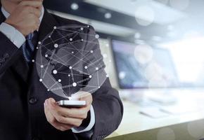 Businessman hand using  mobile phone with social network diagram on wooden desk as concept photo