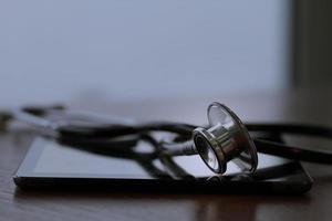 Studio macro of a stethoscope and digital tablet with shallow DOF evenly matched abstract on wood table background copy space photo