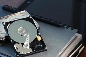 Close up of open computer hard disk drive on desk and notebook photo