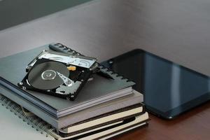 Close up of open computer hard disk drive on desk and notebook photo