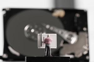 concepto de big data: ingeniero en miniatura que trabaja con una mesa de dibujo con fondo de disco duro abierto foto