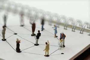 close up of miniature people with social network diagram on open notebook on wooden desk as social media conept photo