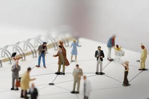close up of miniature people with social network diagram on open notebook on wooden desk as social media conept photo
