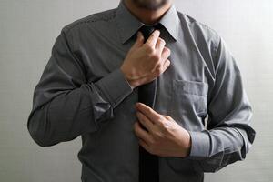 hombre de negocios ajustando corbata, vista frontal, sin cabeza. concepto de trabajar en una oficina. foto