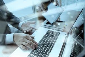 business documents on office table with smart phone and digital tablet and laptop computer and two colleagues discussing data in the background photo