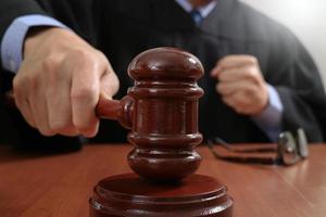 justice and law concept.Male judge in a courtroom striking the gavel,working with digital tablet computer docking keyboard on wood table photo