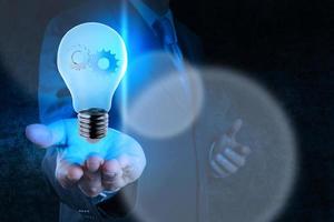 businessman hand showing light bulb with gears as concept photo