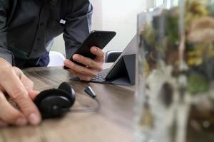 man hand using VOIP headset with digital tablet computer docking keyboard,smart phone,concept communication, it support, call center and customer service help desk with vase flower at foreground photo