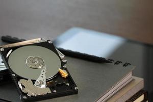 Close up of open computer hard disk drive on desk and notebook photo