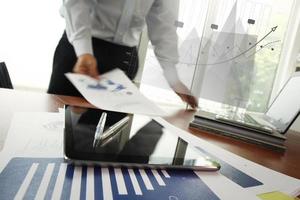 business documents on office table with smart phone and digital tablet and man working in the background photo