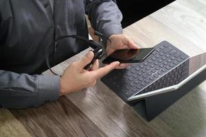 top view of man hand using VOIP headset with digital tablet computer docking keyboard,smart phone,concept communication, it support, call center and customer service help desk on wooden table photo