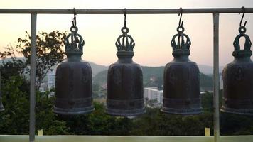metallische glocken, die in einer reihe draußen im thailändischen buddhistischen tempel hängen, thailändische tempelglocke, die glauben, dass wer an diese glocke klopft, das viel glück bekommen wird video