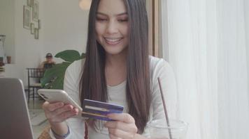 A young beautiful woman is using credit card for shopping online  in coffee shop video