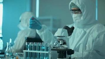 wetenschappers testen op covid-19 door wetenschappelijke buizen te gebruiken voor onderzoek in een laboratorium. video
