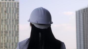 Female construction engineer with a tablet computer at a construction site. Confident woman architect in white helmet looking at a construction site. Construction and architecture concept.