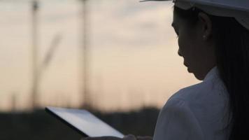 weiblicher Bauingenieur mit einem Tablet-Computer auf einer Baustelle bei Sonnenuntergang. Selbstbewusste Architektin mit weißem Helm, die auf eine Baustelle blickt. video