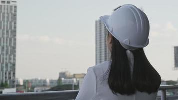 engenheira de construção feminina com um computador tablet em um canteiro de obras. arquiteto de mulher confiante no capacete branco, olhando para um canteiro de obras. conceito de construção e arquitetura. video