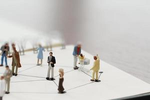 close up of miniature people with social network diagram on open notebook on wooden desk as social media conept photo