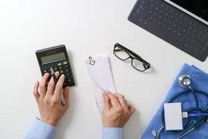 top view of Healthcare costs and fees concept.Hand of smart doctor used a calculator for medical costs in modern hospital photo